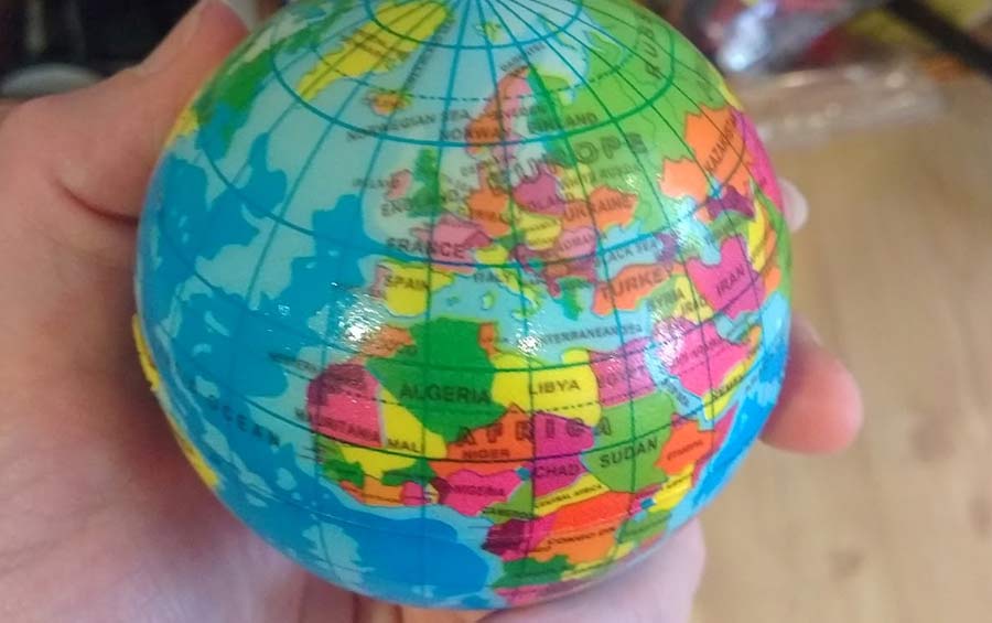 An image of an atlas with brightly coloured world maps displayed